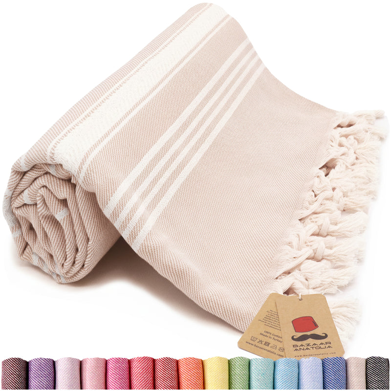 Rolled beige and ivory striped Turkish beach towel with cream tassels, a Bazaar Anatolia tag and color swatches below.