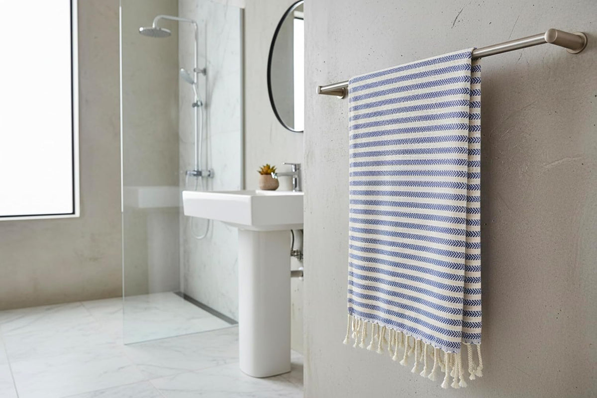 Royal blue Arpa Turkish hand towel hanging from a metal rail in a bathroom.