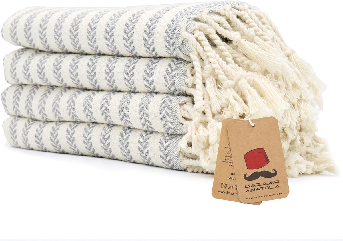 Set of four grey Arpa Turkish cotton hand towels with tasseled ends.