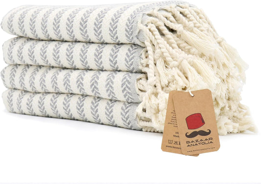 Set of four grey Arpa Turkish cotton hand towels with tasseled ends.