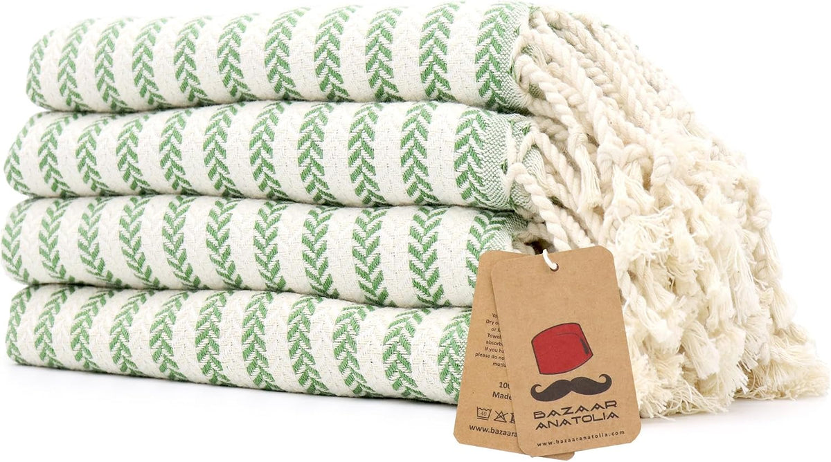 Set of four green Arpa Turkish cotton hand towels with tasseled ends.