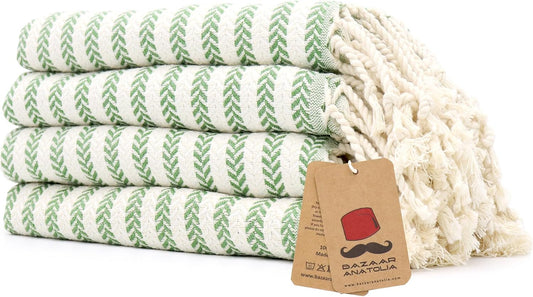 Set of four green Arpa Turkish cotton hand towels with tasseled ends.