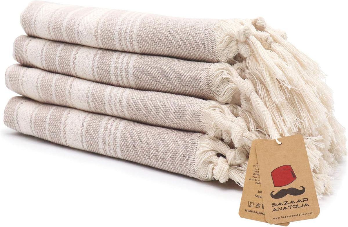Set of four beige Stripe Turkish cotton hand towels with tasseled ends.