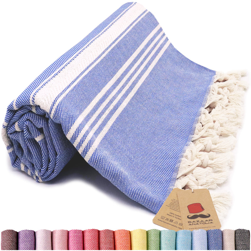 Rolled royal blue and ivory striped Turkish beach towel with cream tassels, a Bazaar Anatolia tag and color swatches below.