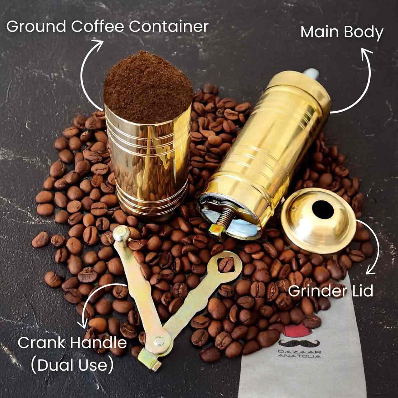 Disassembled brass Turkish coffee grinder showing main body, ground coffee container, grinder lid, and dual-use crank handle, surrounded by coffee beans and a branded Bazaar Anatolia storage pouch.